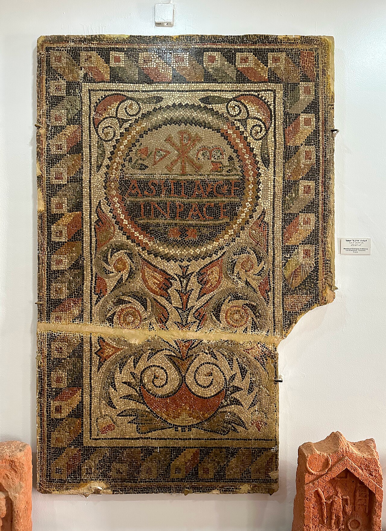 Mosaïque funéraire chrétienne, grand panneau de tesselles avec un chrisme et l’inscription latine IN PACE, accrochée au mur du musée